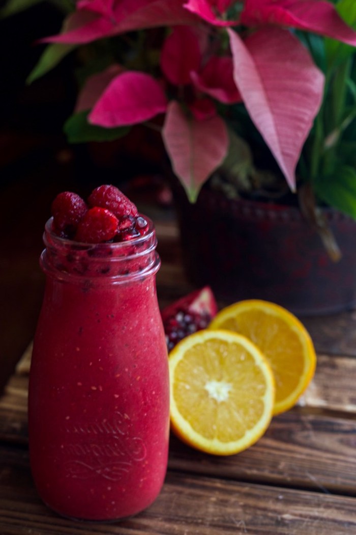 berry and pomegranate smoothie, inside little bottle, topped with raspberries, smoothie recipes, two halves of a lemon nearby