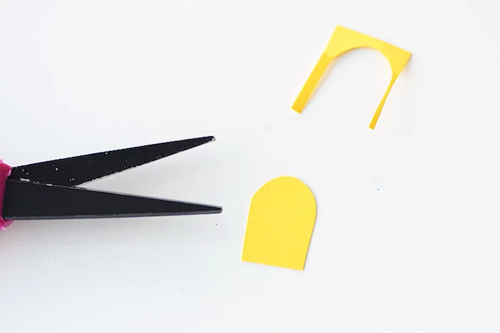 easter projects, scissor blades in black, near a small yellow paper cutout, white background