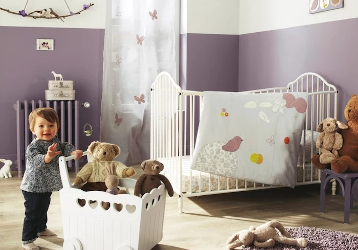 lavender and white walls, in a baby's room, with white metal crib, girl nursery themes, smiling toddler pushing white cart with toys