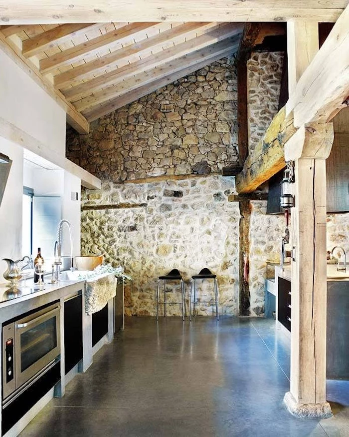 high vaulted ceiling, enforced with wooden planks and beams, inside a large kitchen, with dark smooth floor, modern appliances and stone-covered wall