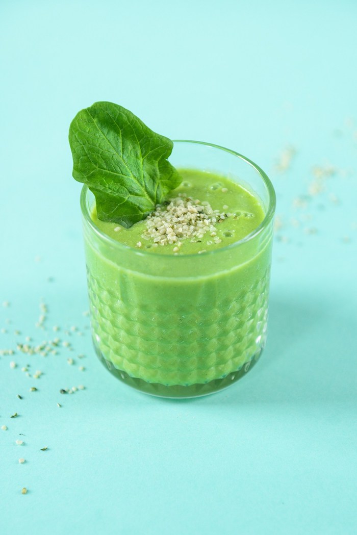 spinach smoothie, inside a small, crystal tumbler glass, with a textured pattern, topped with small seeds