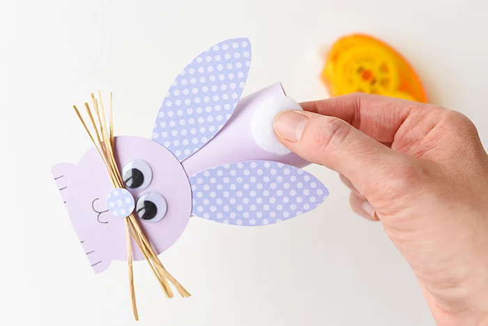 attaching a white cotton ball tail, to bunny figure, made out of pale purple card, easter diy, cute festive idea