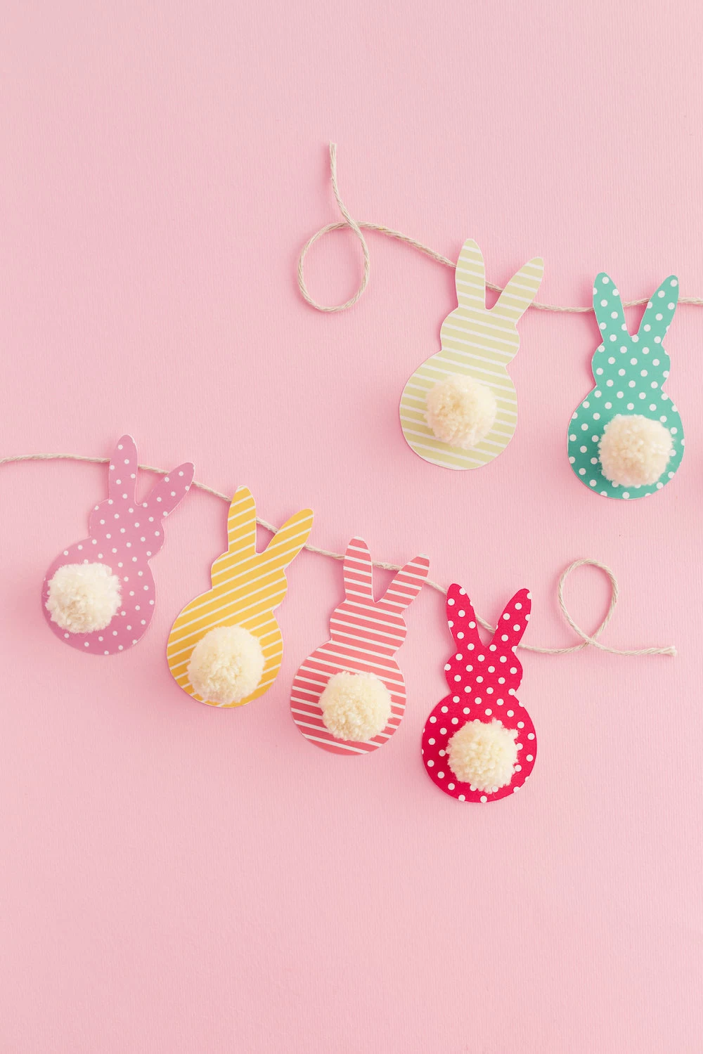 easter crafts for kids, garland made from string, and colorful patterned paper, cut in rabbit shapes, with little white cotton ball tails