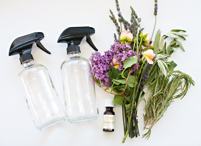 bouquet of flowers and herbs, near two empty clear bottles, with black plastic caps, mother's day gift ideas, and a small bottle of lavender essential oil 