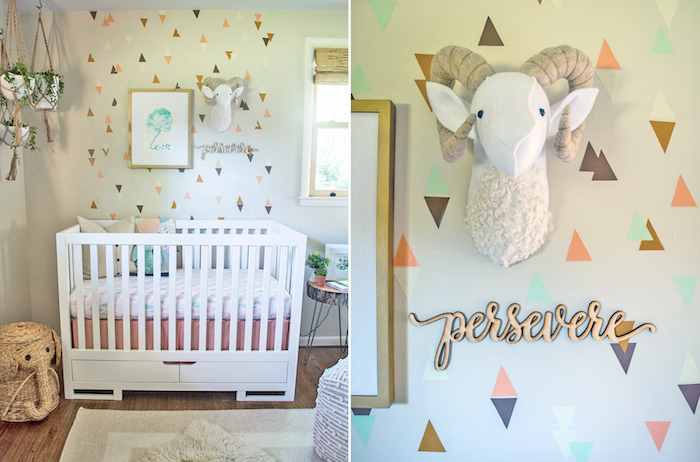 baby girl themes, pale off-white wall, decorated with triangle shapes, in natural colors, with white wooden crib, plush ram's head decoration, and hanging potted plants