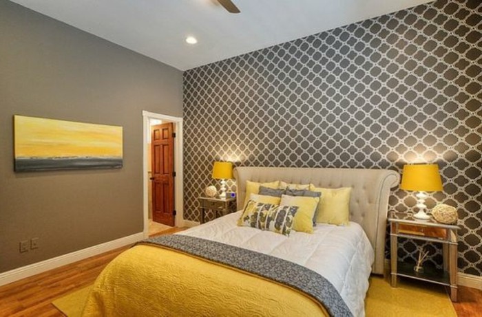 painting in yellow and gray, inside grey bedroom, with patterned wallpaper, pale beige bed, white and gray, and yellow bedding