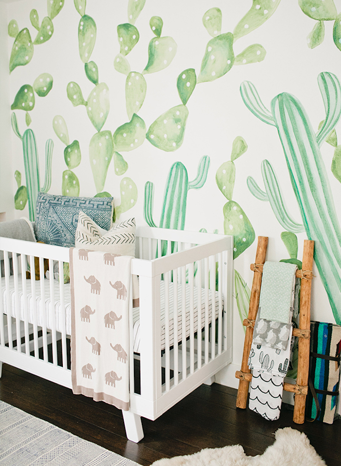 gender neutral nursery, watercolor effect wallpaper, with light green cacti pattern, white wooden baby crib, dark wooden floor, nature inspired room