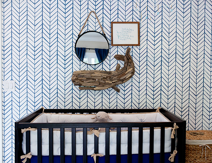 round wall mirror, near framed text, and wooden whale ornament, boys room ideas, black wooden crib, white and blue wallpaper