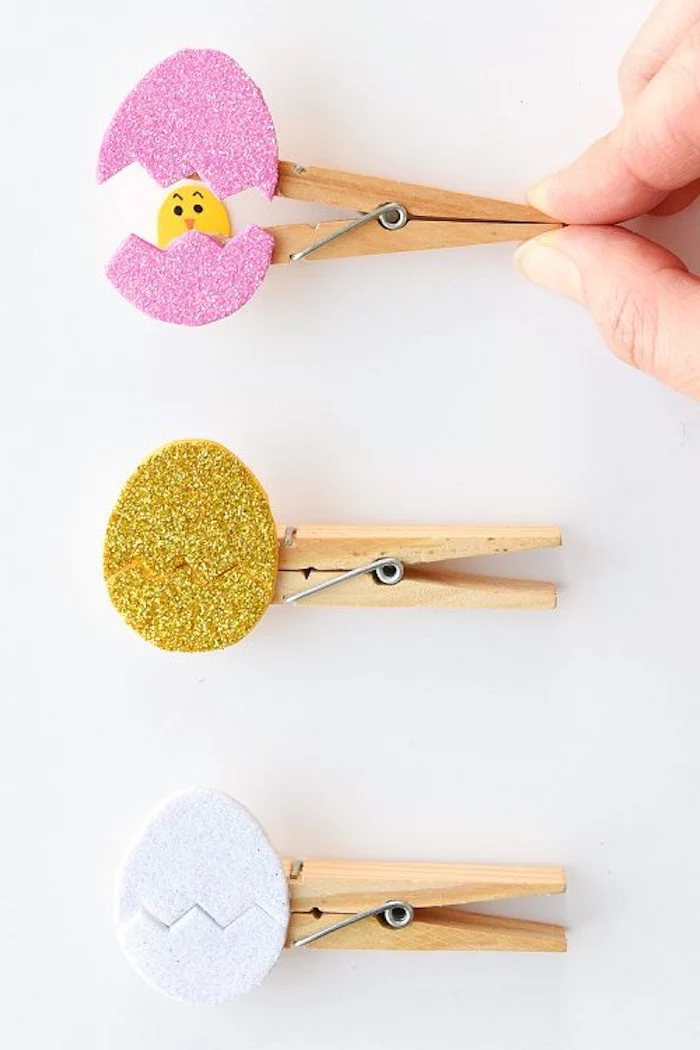 hatching egg ornaments, containing yellow paper chicks, easter arts and crafts, made with glittering card, in different colors, and wooden clothespins