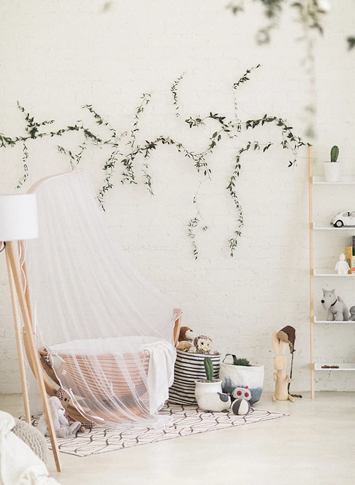 organic nature-inspired, gender neutral nursery, with white walls, wooden baby basket, with sheer white baldachin, various green plants and toys 