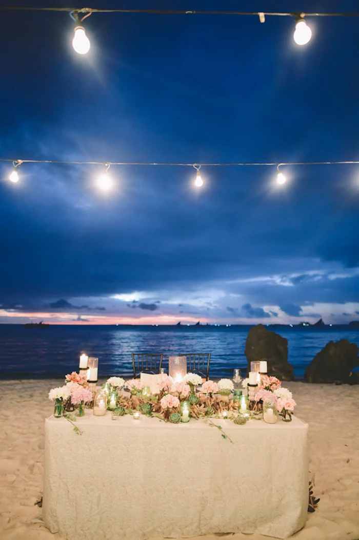 evening wedding near the sea, lavishly decorated table, with lots of flowers, florida destination weddings, string lights and candles