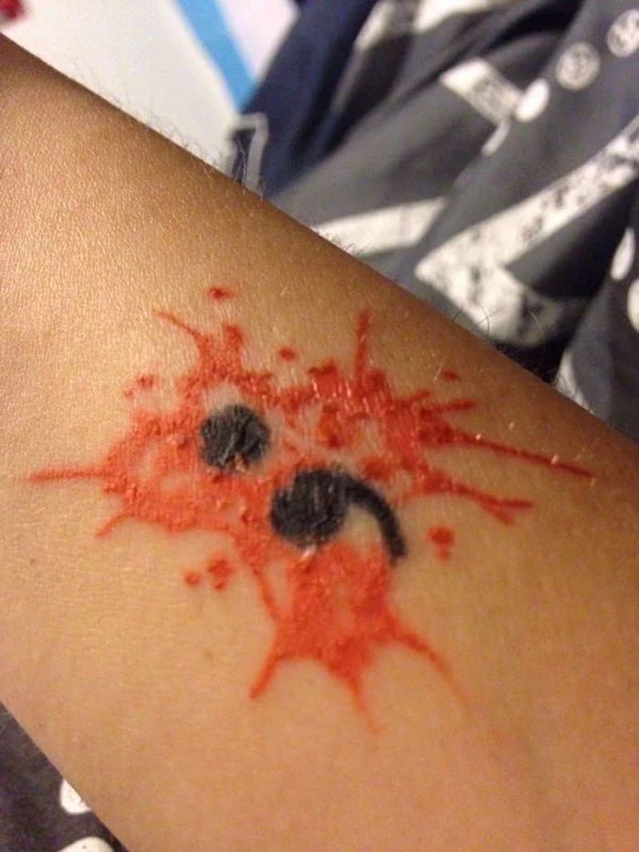person's arm decorated with a red tattoo, resembling a blood splatter, with a black semicolon in the middle, what does a semicolon tattoo mean, unusual original design