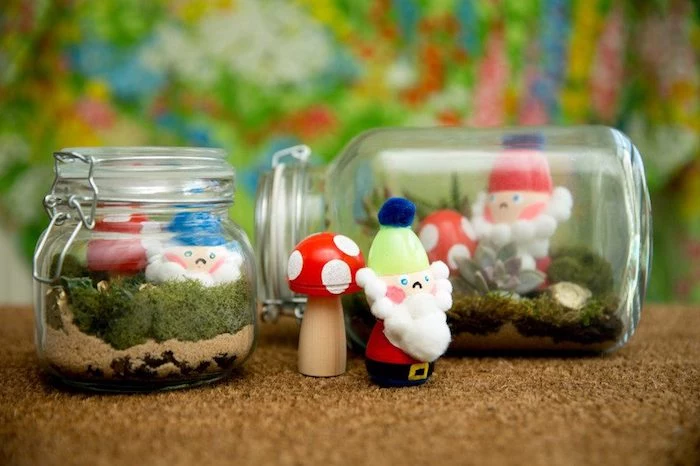 jars with snap lids, filled with fine beige sand, green moss and succulent, with little figurines, succulent fairy garden, painted wooden mushrooms and gnomes