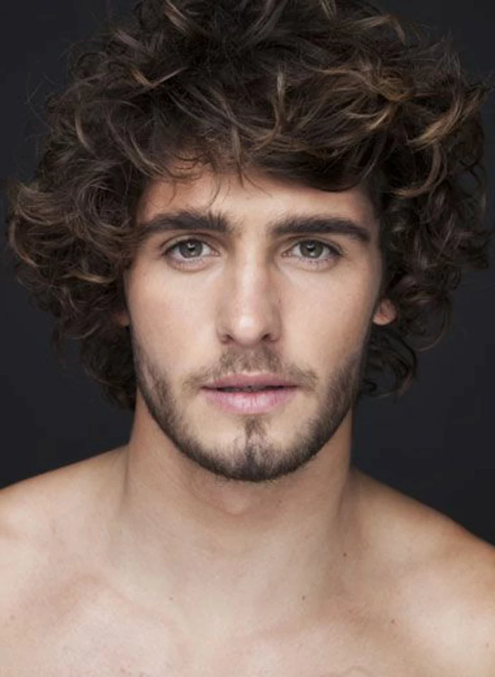haircuts for men with curly hair, topless man with short beard and a mustache, brown eyes and bushy eyebrows, voluminous unruly brunette hair