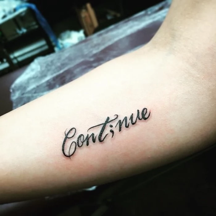 elegant black font, spelling the word continue,but with the i replaced with a semicolon, tattooed on the inside of a person's arm, semicolon tattoo meaning, spreading awareness for suicide prevention