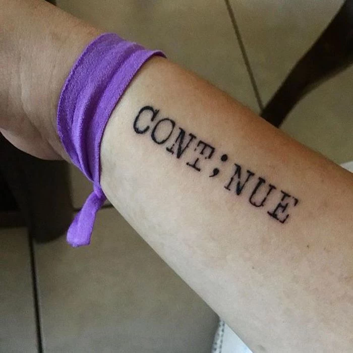 purple fabric wristband, tied to a person's hand, what does a semicolon tattoo mean, the word continue tattooed in a black, typewriter style font, the i replaced by a semicolon