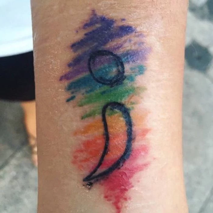 rainbow crayon scribble effect tattoo, with black semicolon outline, semicolon tattoo meaning, on a slim person's wrist