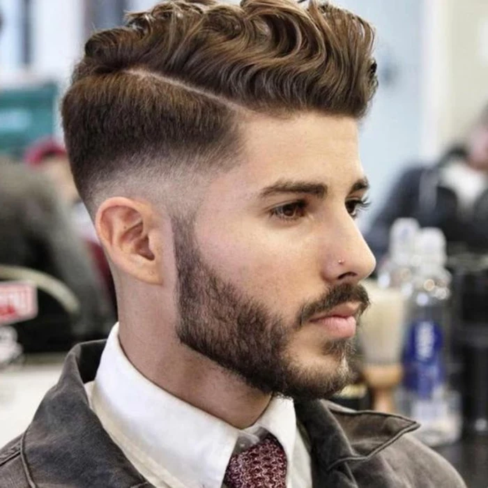 haircuts for curly hair, faded undercut with deep side part, curls swept to one side, trimmed beard and a mustache, white shirt with patterned tie