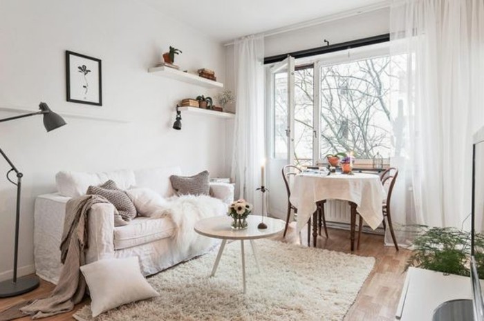 balcony with open door, and sheer white curtains, attached to room decorated in light colors, sofa with several cushions, small apartment living room ideas, cream fluffy rug, round coffee table