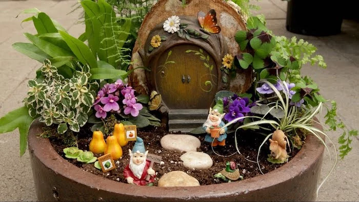 turte and snail, squirrel and gnome, and tiny gourd figurines, decorating a large ceramic pot, containing small burrow-like house ornament, fairy garden pictures, various flowers and plants