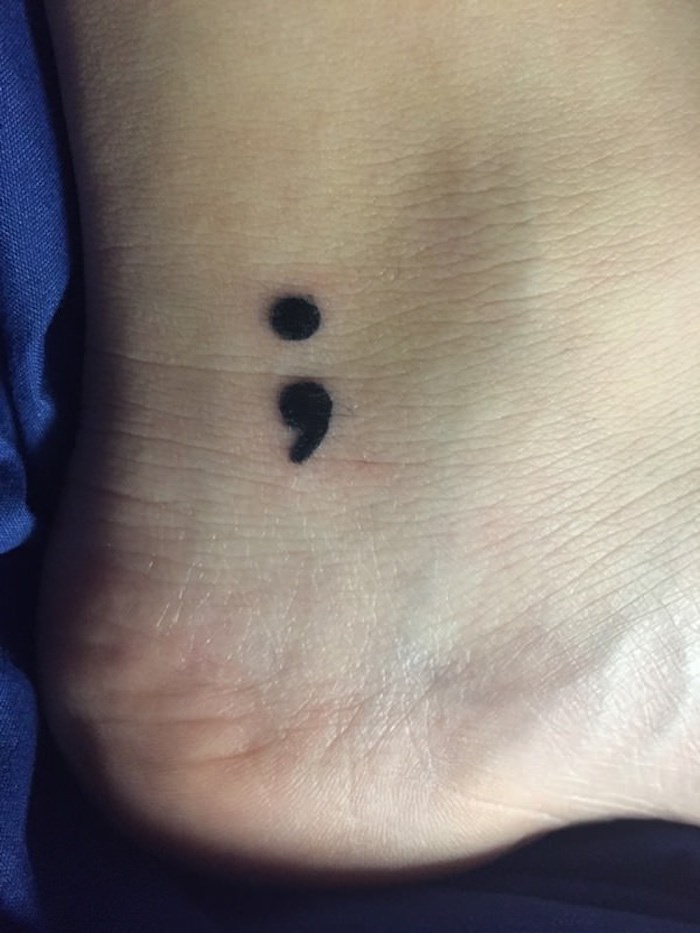 human heel with a black semicolon tattoo, minimalistic design and small size, suicide awareness tattoo, extreme close up, smooth pale skin