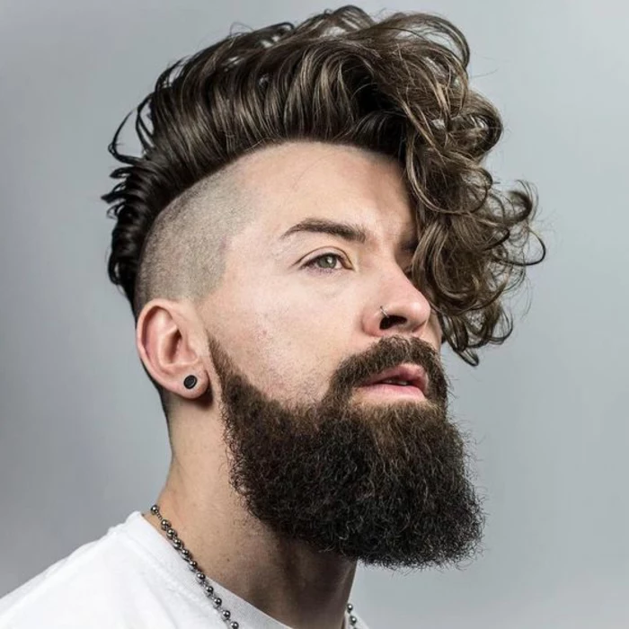 long beard with mustache, worn by hipster style man, with deep curly undercut, brushed to one side, hairstyles for curly hair, nose ring and black earring