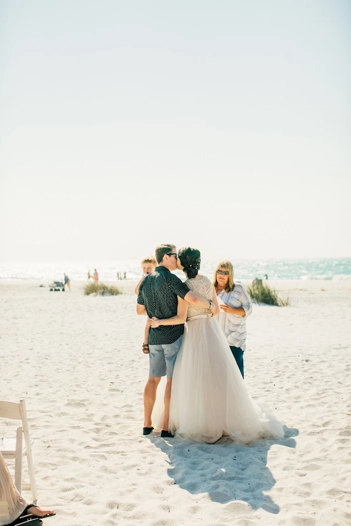 florida destination weddings, kissing couple at the beach, bride in floaty embroidered dress, with tulle skirt, and groom in denim shorts, and dark casual shirt