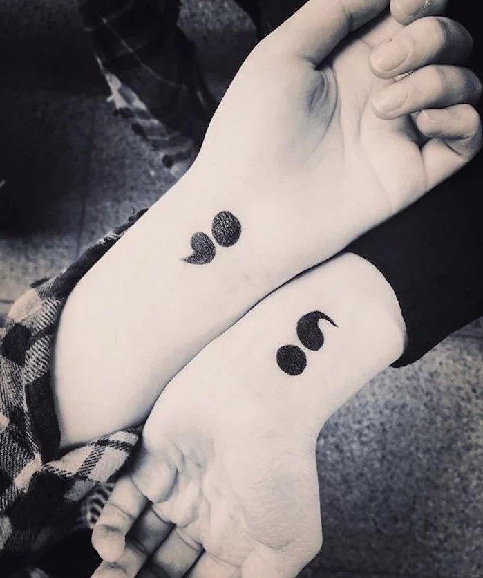 bold matching tattoos of semicolons in black, on the wrists of two hands, placed next to each other, suicide awareness tattoo