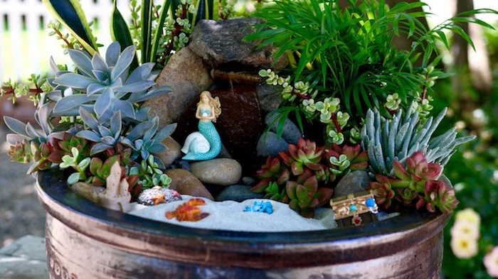 sea-side inspired succulent fairy garden, with fine gray sand, and tiny figurines, treasure chest and grabs, sand castle and mermaid