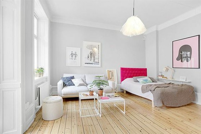 wooden floor in pale beige, inside room with white and pale gray walls, bed with hot pink board, apartment design, white sofa and two coffee tables