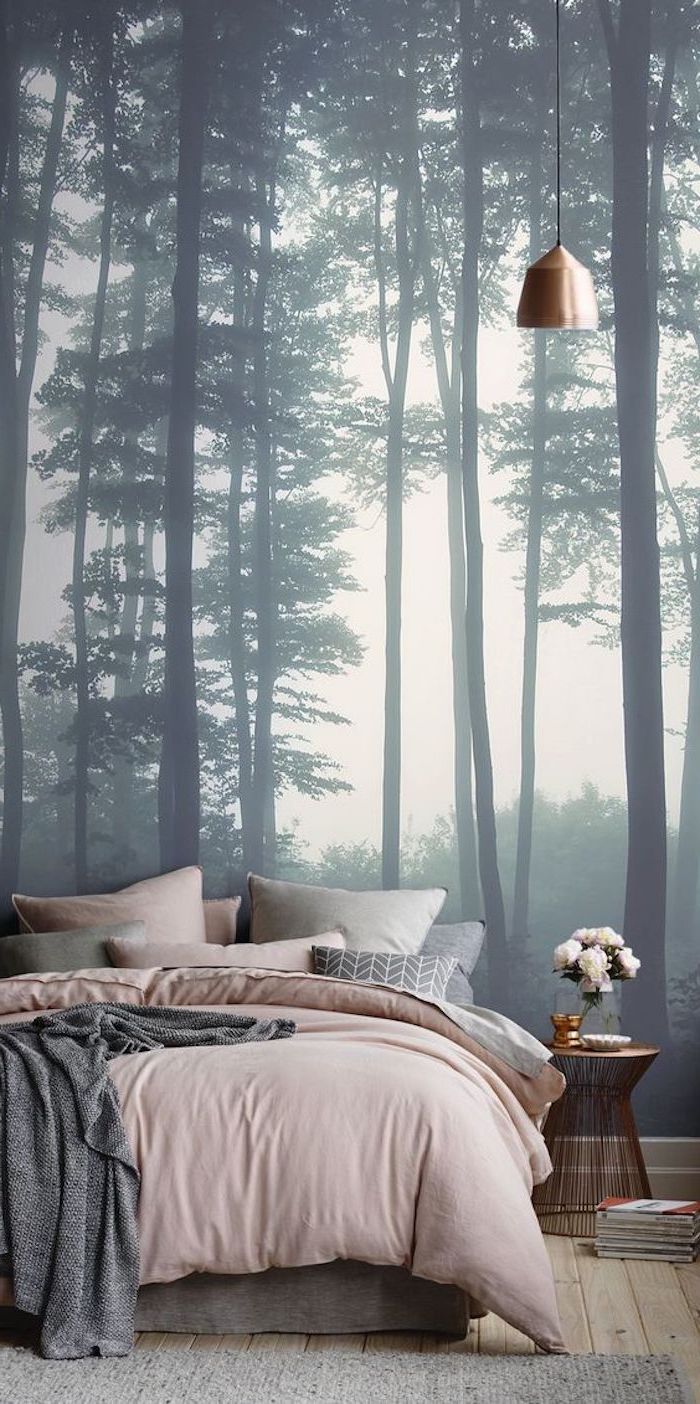 forest with gray misty trees, ambient photo wallpaper, near bed with pastel pink, and pale gray covers and cushions, large wall art, in room with high ceiling