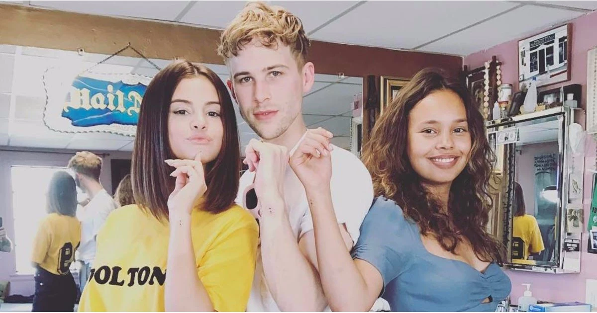 alisha boe standing next to tommy dorfman, and selena gomez, all showing their arms with identical, small black semicolon tattoo designs