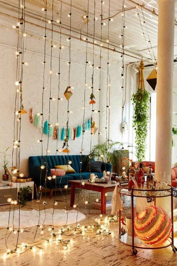 curtain made from lit string lights, inside studio with dark blue sofa, and wooden coffee table, small apartment living room ideas, several potted plants and colorful decorations