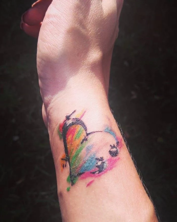heart tattoo in a smudged, watercolor-like style, decorated with rainbow colors, subtle semicolon project tattoo, on the side of a person's wrist