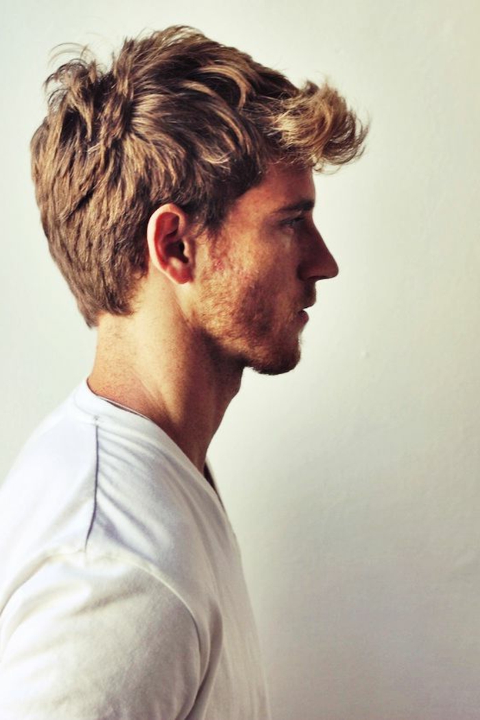 classical man's hairstyle, on young guy, dressed in white t-shirt, with stubble on his chin and cheeks, standing in profile