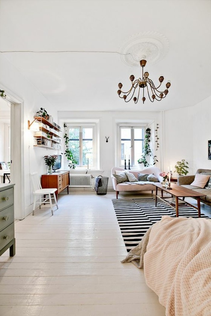 antique ornamental chandelier, hanging inside spacious room, with two windows and white wooden floor, studio apartment decorating ideas, two retro sofas and coffee table, bed and striped rug