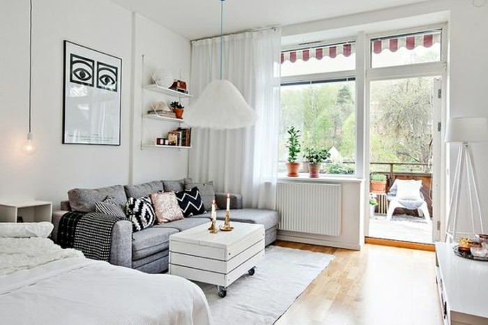 open terrace attached to a bright room, white walls and sheer white curtains, pale gray sofa and white bed, small apartment ideas, laminate floor and white rustic coffee table