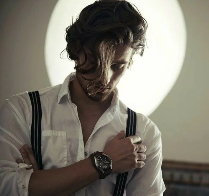 strand of hair, falling over a man's face, guys with curly hair, white shirt and suspenders, large wrist watch, stubble on chin