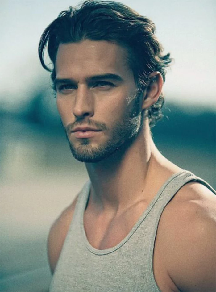 slicked back wavy dark hair, on man with very short beard and mustache, haircuts for men with curly hair, light grey top