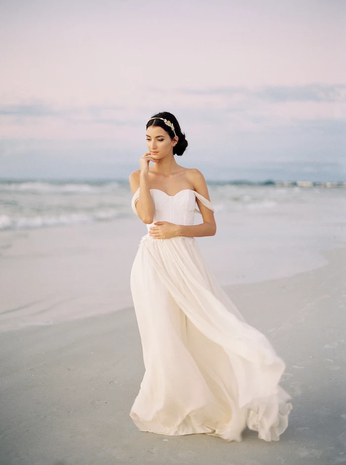 flowy white dress, with slouched shoulder straps, worn by young woman, with dark hair tied back, and silver tiara, beach wedding at sunset