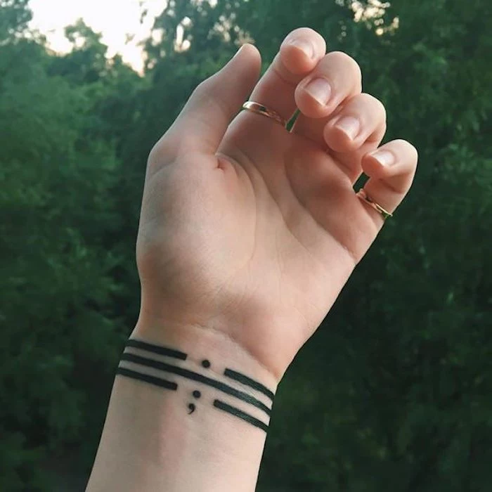semicolon project tattoo, three black stripes, around a person's wrist, one punctuated by a full stop, on punctuated by a semicolon, and one unpunctuated