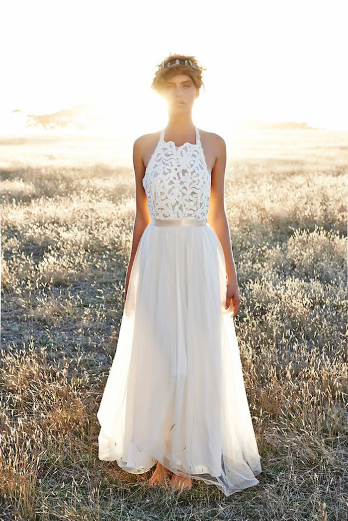 field with dry grass at sunset, slim woman standing barefoot, dressed in a long white gown, with embroidered top, and a floaty tulle skirt