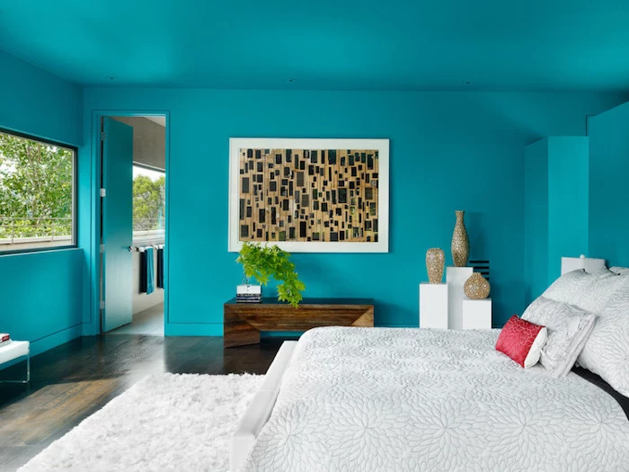bedroom design, turquoise colored walls and door, large framed abstract painting, double bed and fluffy rug, dark laminate floor