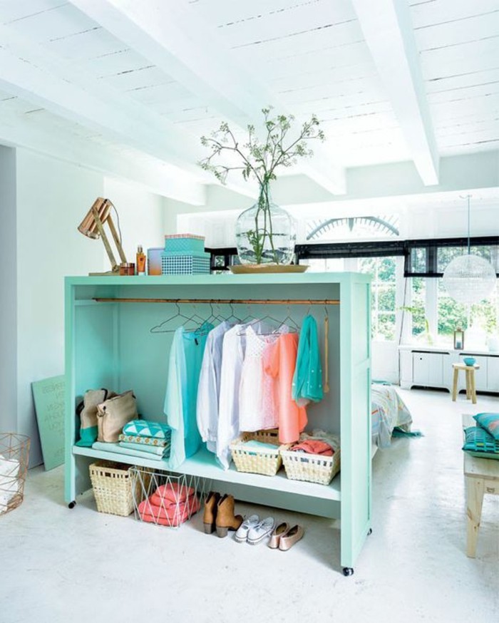 white ceiling with wooden beams, inside spacious room, with white floor, apartment design, turquoise clothes rack, with several pieces of clothing, and other items 