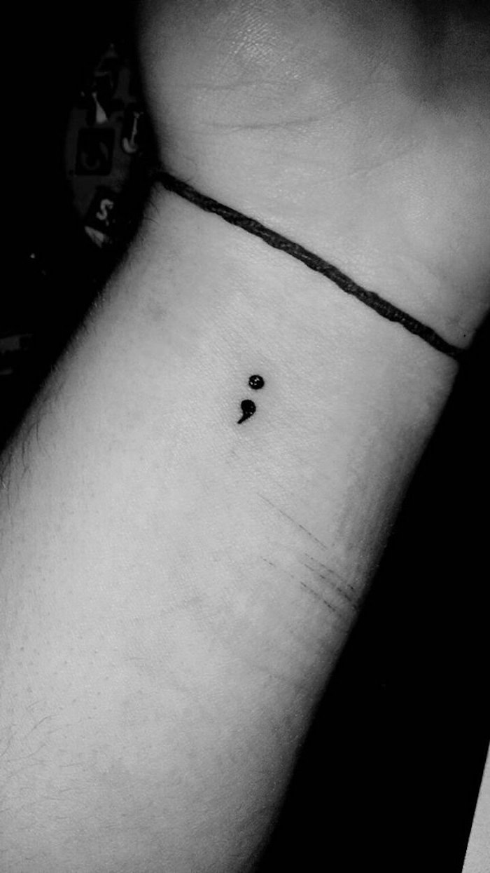 scarred wrist with hand-drawn temporary tattoo, consisting of a black continuous line, and tiny semicolon, semicolon tattoo on wrist, in a black and white image