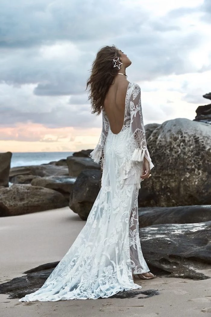 big hoop earring, with star-shaped decoration, worn by tan brunette woman, beach wedding, white lace boho gown, with tassels and sheer details, and cutout back