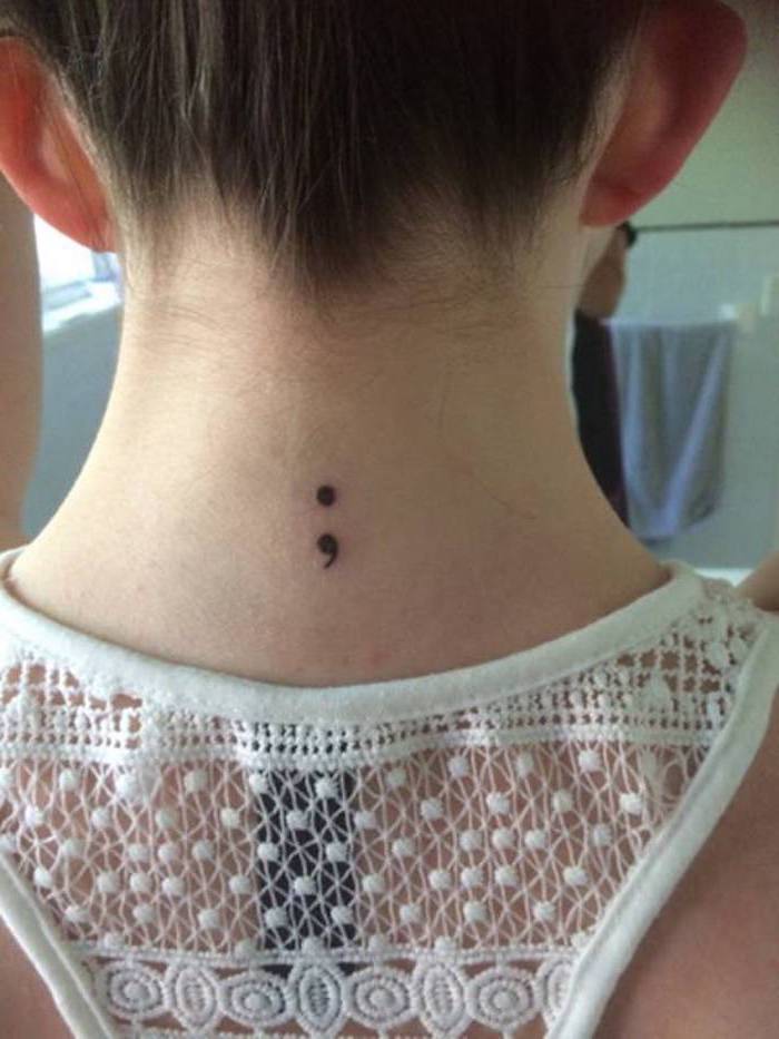 white lace cutout top, worn by a girl, with brunette hair tied up, to reveal a small black semicolon tattoo, on the nape of her neck