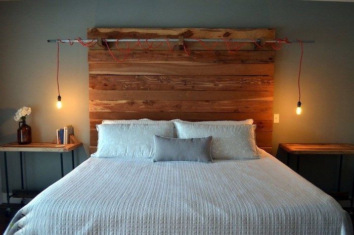 two lit light bulbs, hanging from a red cable, attached to a metal pole, bedroom design, wooden headboard made from reclaimed wood