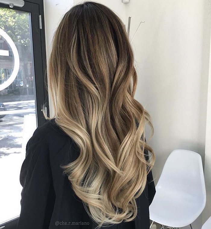 lady in black top, seen from the back, with long brunette hair, styled in loose waves, and decorated with ash blonde highlights, balayage brown hair