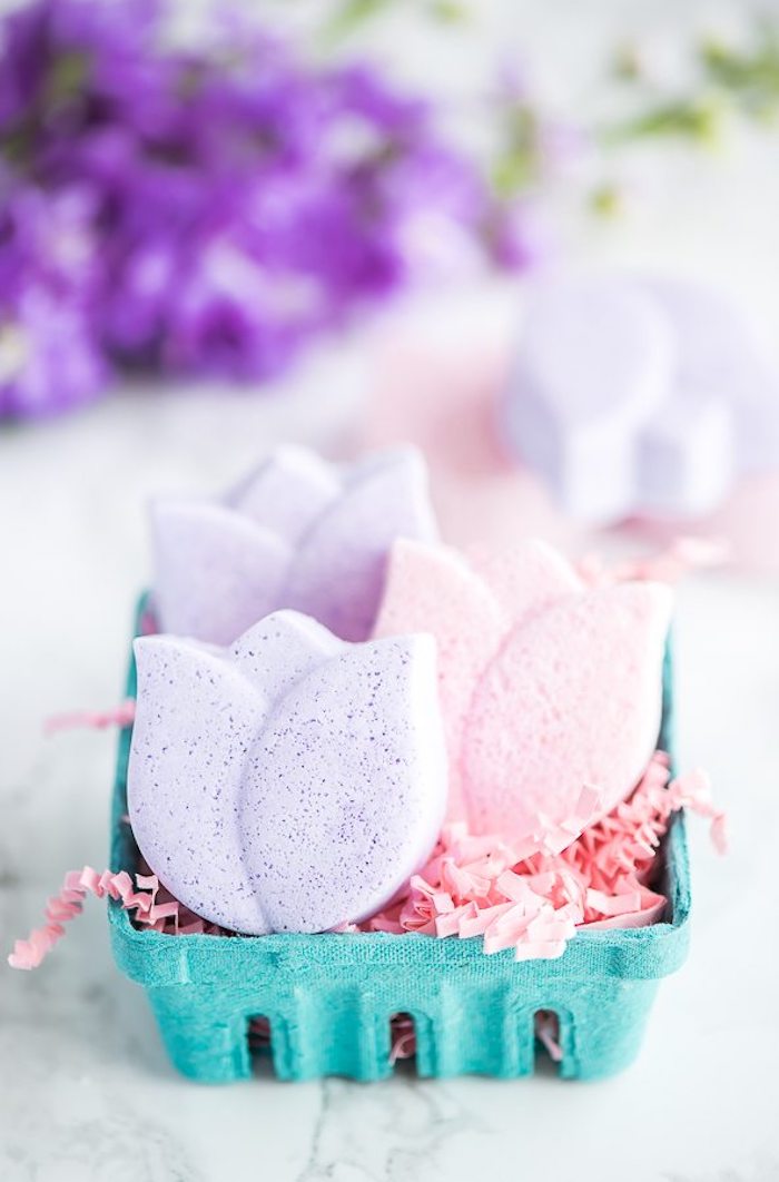 tulip diy bath bombs, in pale violet, and light pastel pink, placed on pink easter grass, inside a teal blue cardboard box